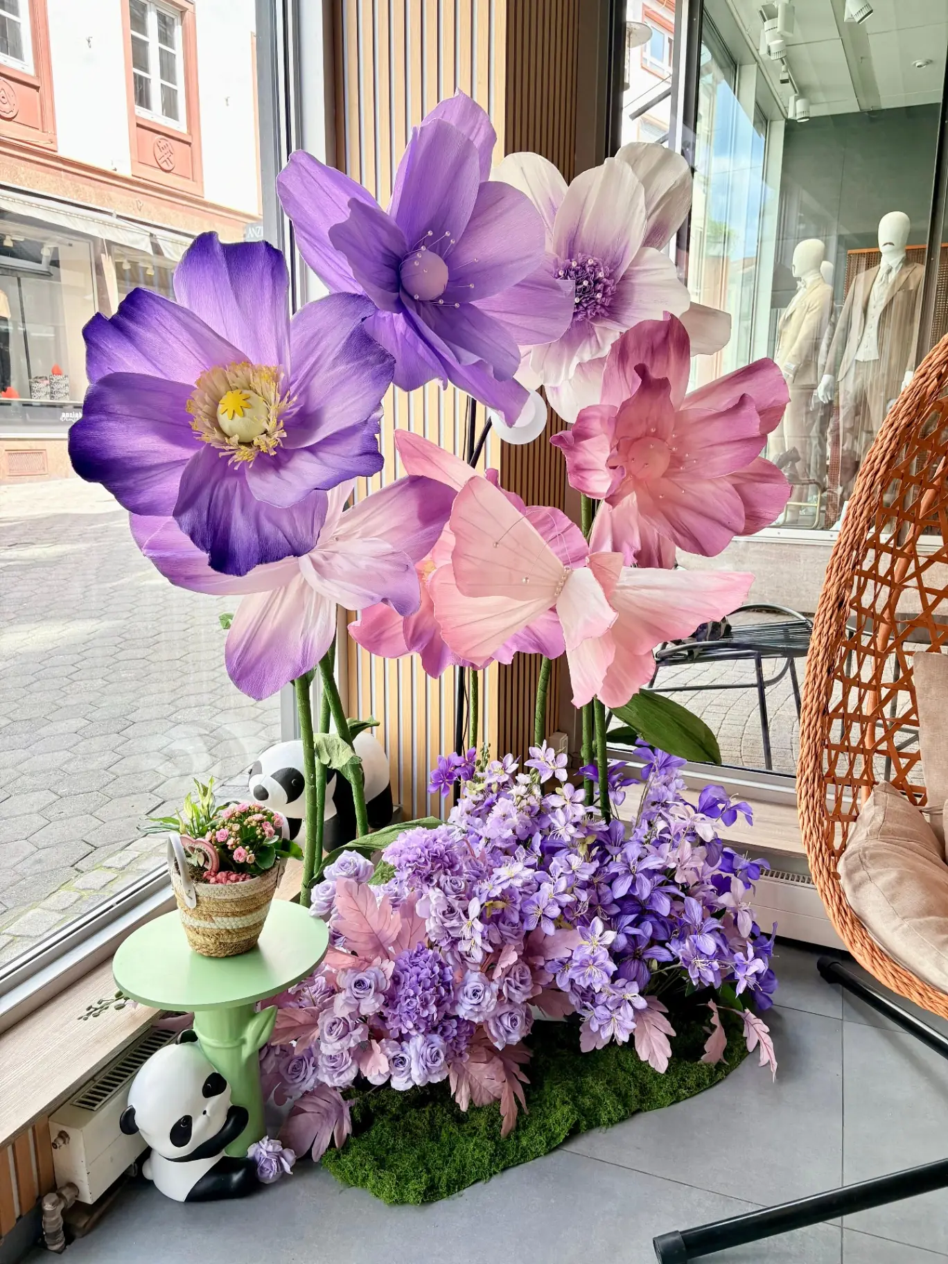 Große Papierblüten in Lila und Rosa mit Panda-Figuren am Eingang des Panda YuAi Cafés