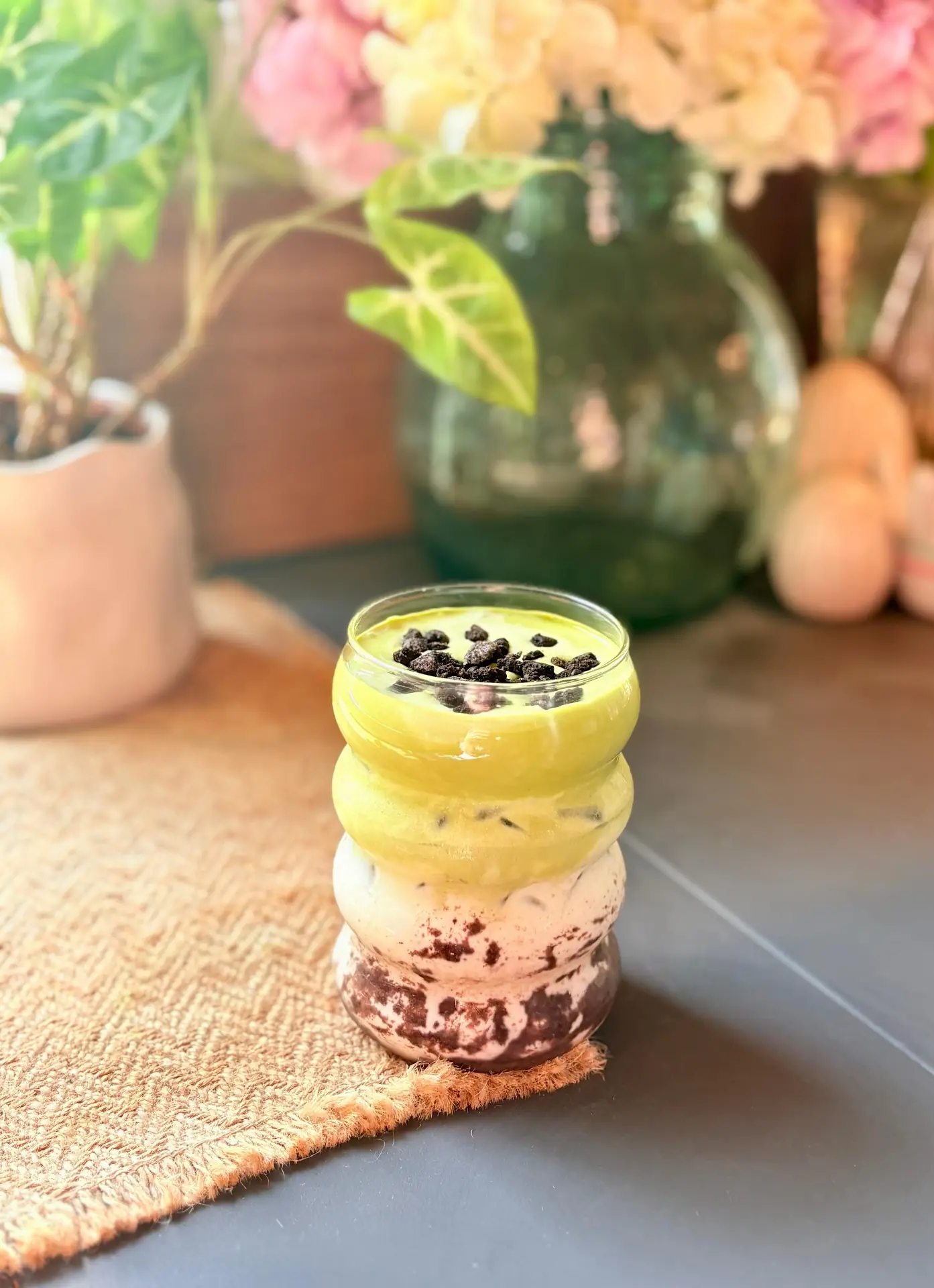 Oreo Matcha Creme im Glas vor Blumen