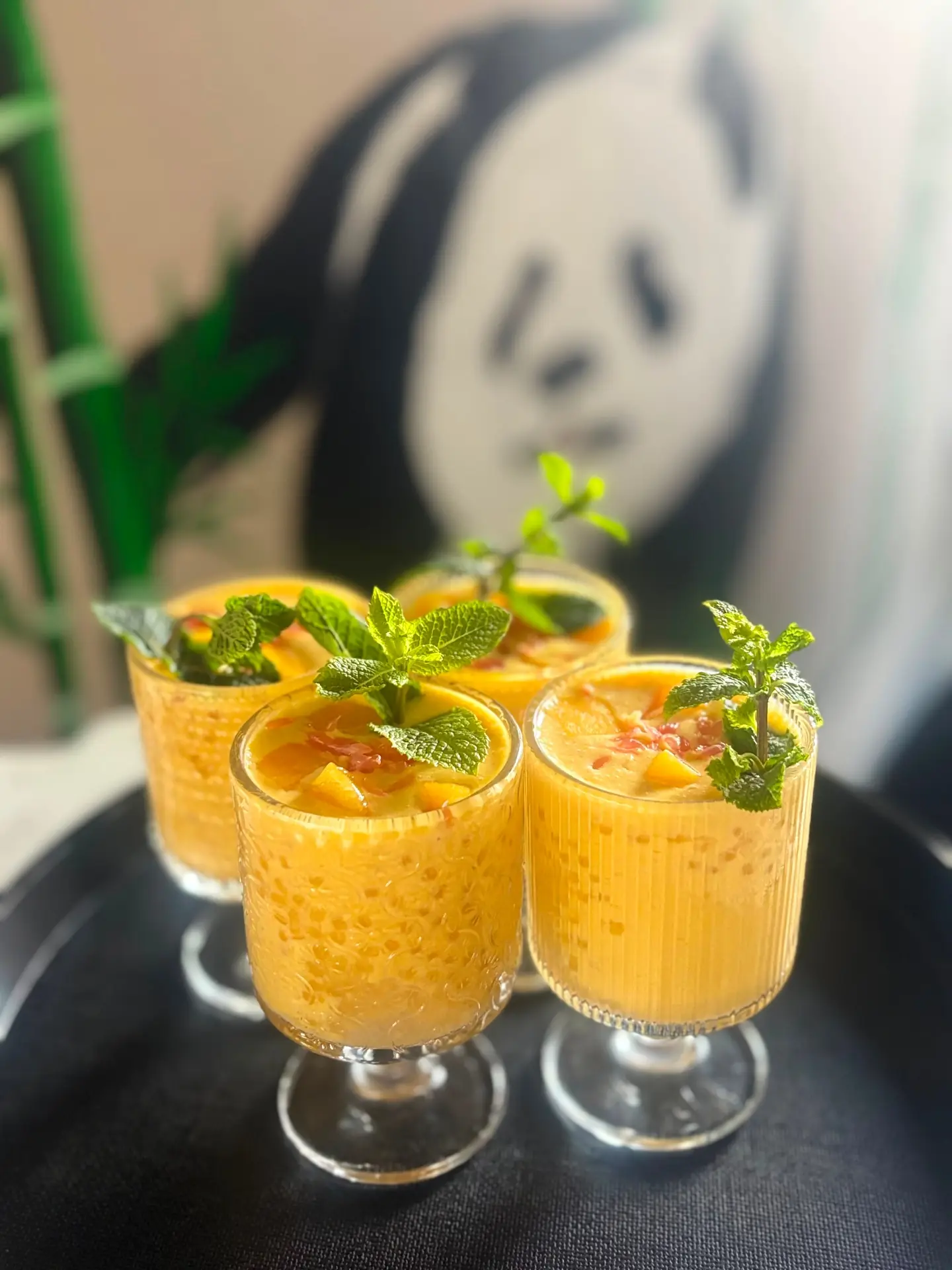 Frisches Mango-Dessert mit Minze vor einem Panda-Wandbild
