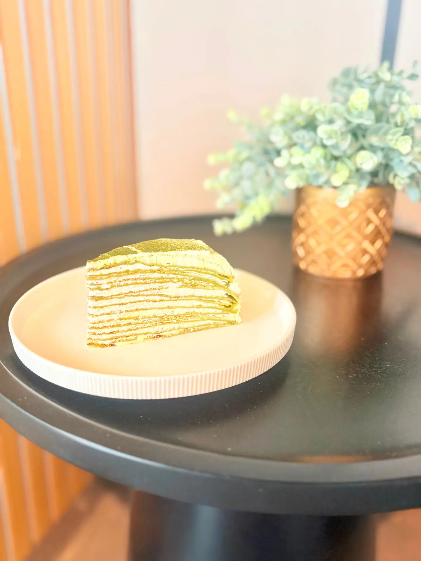 Stück Matcha-Crêpe-Torte auf einem Teller im Café