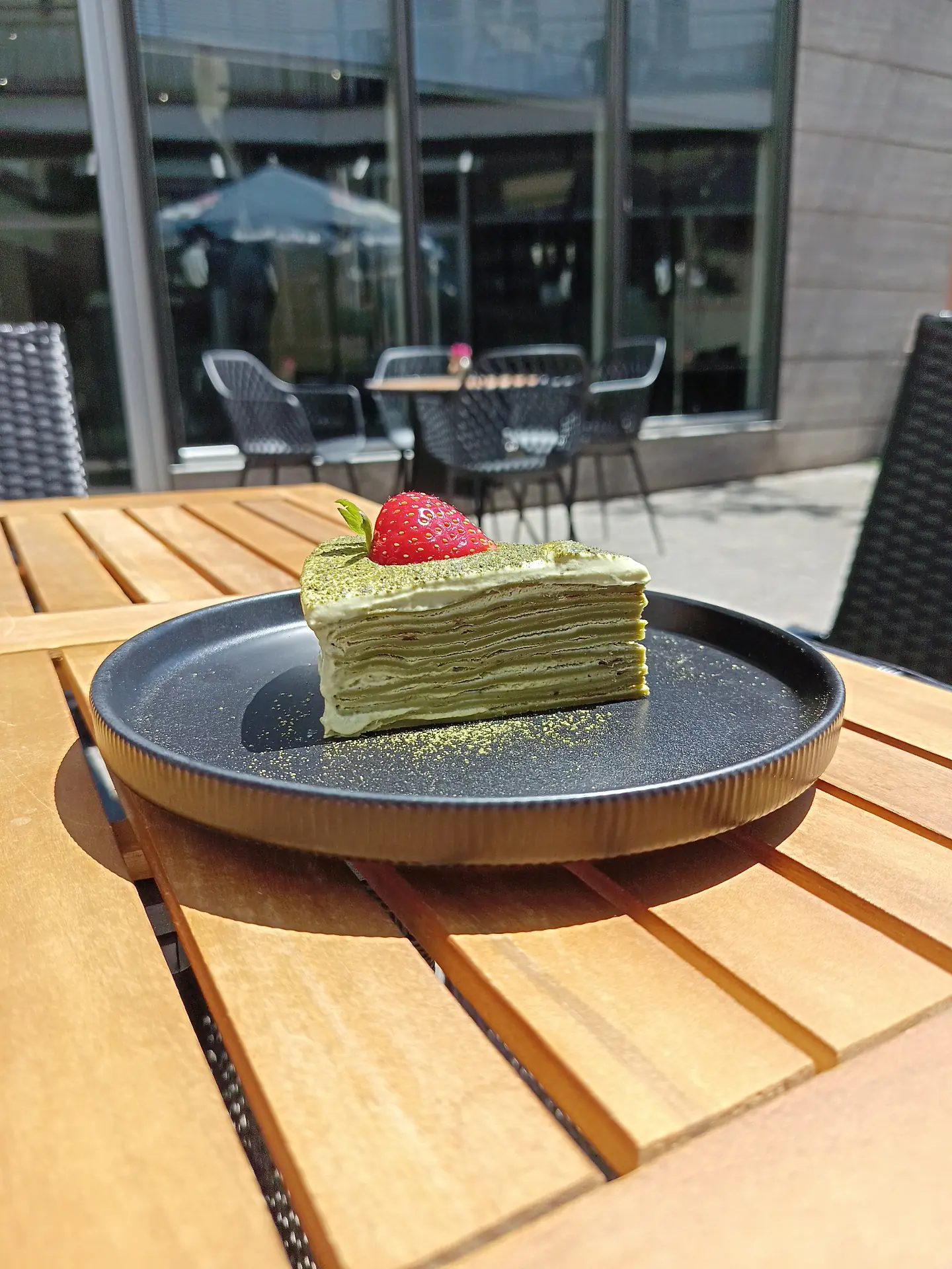 Stück Matcha-Crêpe-Torte mit Erdbeere auf der Terrasse des Panda YuAi