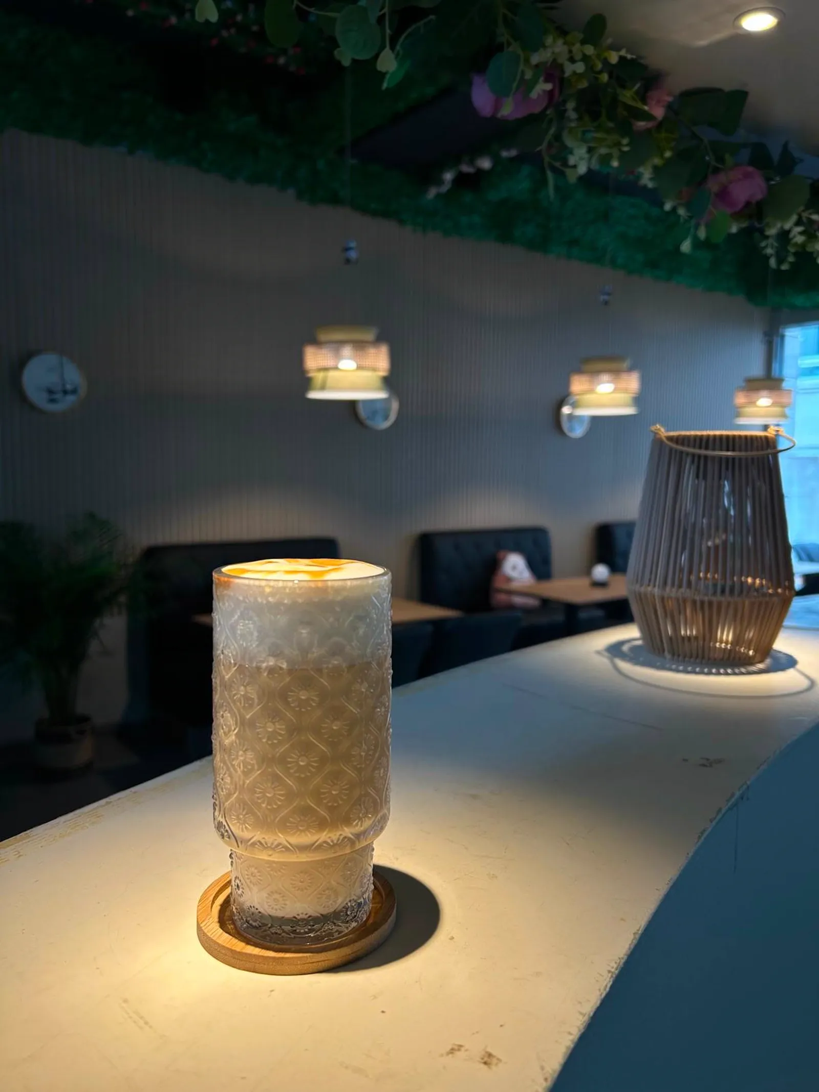 Latte im Relief-Glas auf der Theke im abendlich beleuchteten Café